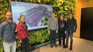 Projektteam vor Großbildschirm mit BIM-As-built-Modell einer Kita im begrünten Präsentationsraum